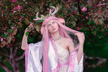 Deer dryad girl against the background of a blooming pink apple tree