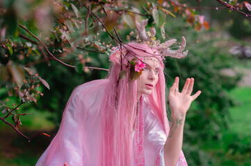 Deer dryad girl against the background of a blooming pink apple tree