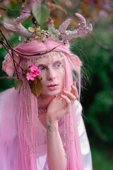 Deer dryad girl against the background of a blooming pink apple tree