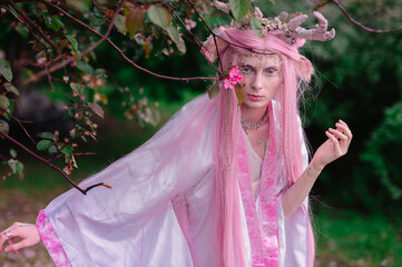 Fototapeta premium Deer dryad girl against the background of a blooming pink apple tree