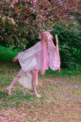 Deer dryad girl against the background of a blooming pink apple tree