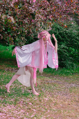 Deer dryad girl against the background of a blooming pink apple tree