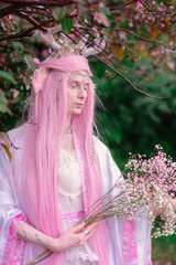 Deer dryad girl against the background of a blooming pink apple tree