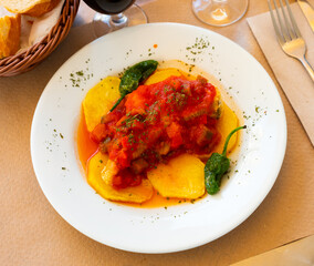 Delicious fried cod served on plate with vegetables samfaina..