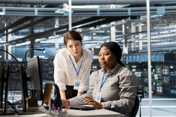 Manager overseeing work done by engineer in server hub, analyzing rigs data. Data center office...