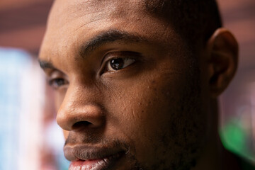 Obraz premium Focus on man eyes with pensive reflective look doing ruminating in apartment. African american person with focused expression lost in deep thoughts, extreme close up shot