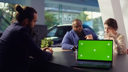 Dealership salesperson looking over appointment list on green screen laptop spreadsheet to schedule car test drive for customers. Showroom agent organizing test drive using mockup notebook, camera B