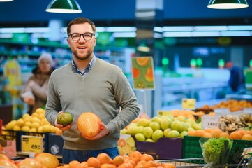 A man chooses fruits in a supermarket with a shopping cart