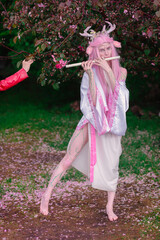 Deer dryad girl against the background of a blooming pink apple tree