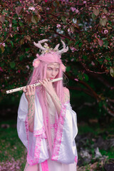 Deer dryad girl against the background of a blooming pink apple tree