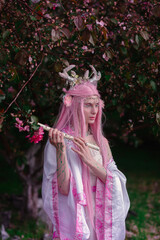 Deer dryad girl against the background of a blooming pink apple tree