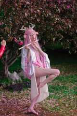 Deer dryad girl against the background of a blooming pink apple tree