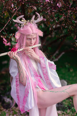 Deer dryad girl against the background of a blooming pink apple tree