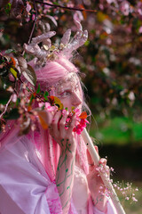 Deer dryad girl against the background of a blooming pink apple tree