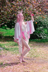 Deer dryad girl against the background of a blooming pink apple tree