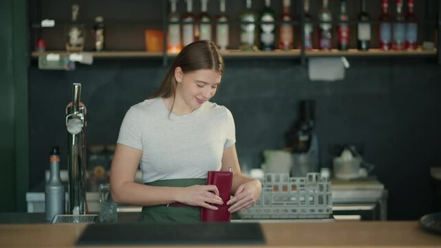 Smiling barista counting tips and closing her wallet
