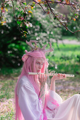 Deer dryad girl against the background of a blooming pink apple tree