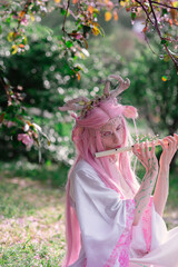 Deer dryad girl against the background of a blooming pink apple tree