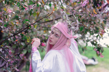 Deer dryad girl against the background of a blooming pink apple tree