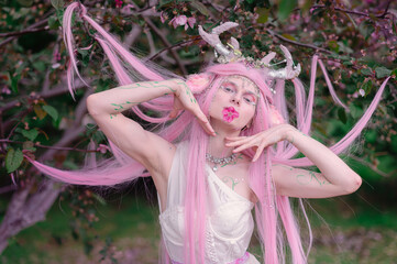 Deer dryad girl against the background of a blooming pink apple tree