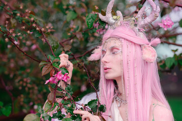Deer dryad girl against the background of a blooming pink apple tree