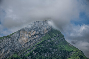 Clouds enveloping a rugged mountain peak in a serene landscape during the day in a natural setting