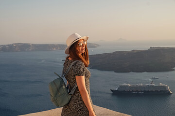 Woman enjoying scenic view of coastal landscape at sunset in Santorini, Greece