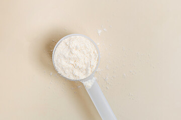 Vanilla protein powder in plastic scoop on neutral background