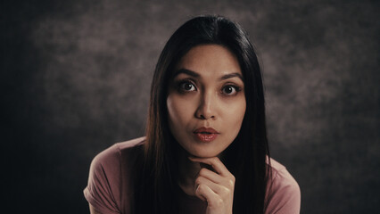 Woman with long hair reflecting deeply, resting chin on hand