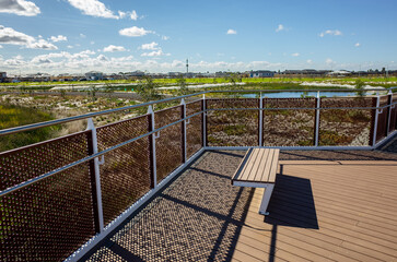Elevated viewing platform with seating overlooking a rehabilitated wetland and new housing estate...