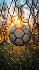 Soccer ball in a goal net at sunset