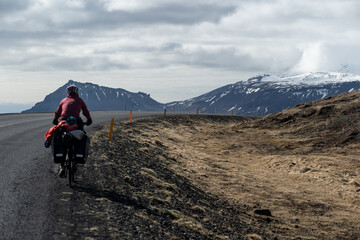 View of mountains on the Sn&aelig;fellsnes peninsula in Iceland with woman on a bike in the foreground.