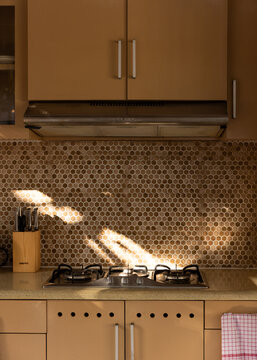 Traditional modernized kitchen in Bali villa with tile, gas stove, and sun dapple. 