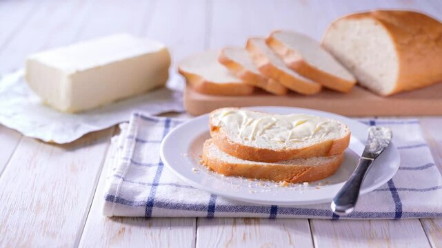 Slices of wheat bread and butter on a white wooden table.Delicious white wheat bread and fresh butter on a light wooden table.
