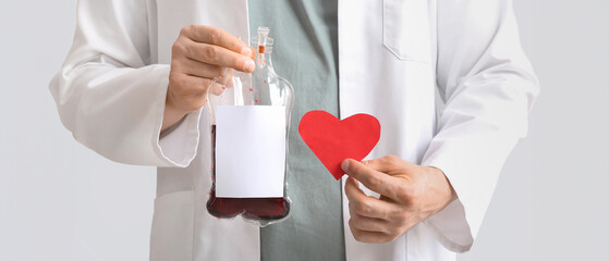 Doctor with blood pack and paper heart on grey background, closeup. Blood donation concept