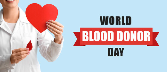 Female doctor with paper heart and blood drop on blue background, closeup