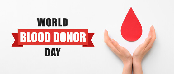 Female hands with paper blood drop on white background. World Blood Donor Day