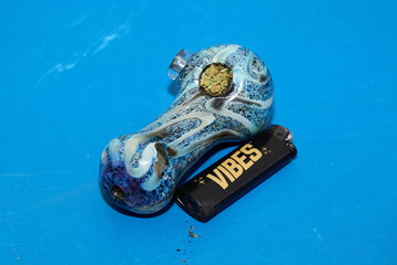 Blue Glass Pipe with Vibes Lighter on Blue Background
