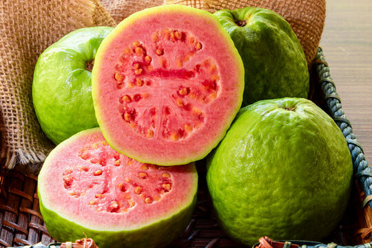 Closeup on red guava sliced with green leaf on rustic wooden background