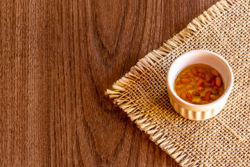 Small bowl with oil and pepper on rustic wooden background