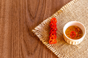 Small bowl with oil and pepper on rustic wooden background
