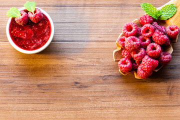 Spoon with raspberry and bowl with raspberry jam on wooden background