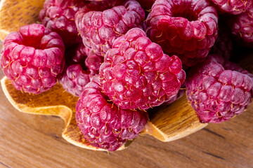 Spoon with raspberry and bowl with raspberry jam on wooden background
