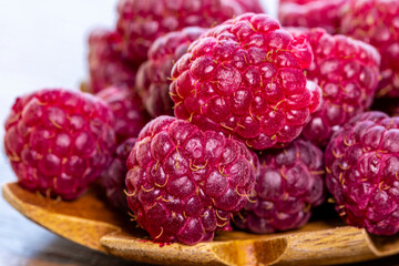 Spoon with raspberry and bowl with raspberry jam on wooden background