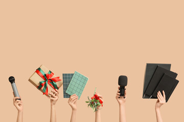 Journalist's female hands with Christmas gift boxes, notebooks and microphones on beige background