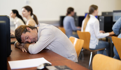 Adult man fell asleep at table while working at computer in office
