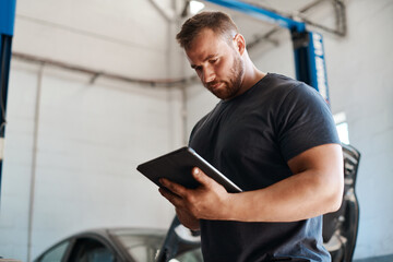 Man, car mechanic and workshop with tablet for maintenance or inspection with online information...