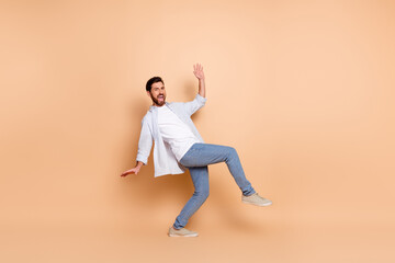 Young casual man making a dynamic gesture on peach background showcasing trendy style and fashion with expressive movement
