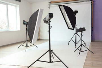 Interior of photo studio with professional equipment and white backdrop