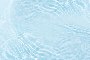 Blue water with ripples on the surface. Defocus blurred transparent blue colored clear calm water surface texture with splashes and bubbles. Water waves with shining pattern texture background.